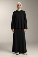 Black knit sweater and maxi skirt on a hijabi model in a neutral studio